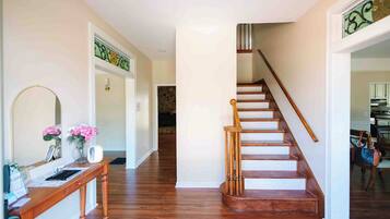 A hallway with a wooden staircase, a reception desk, and a door leading to another room.