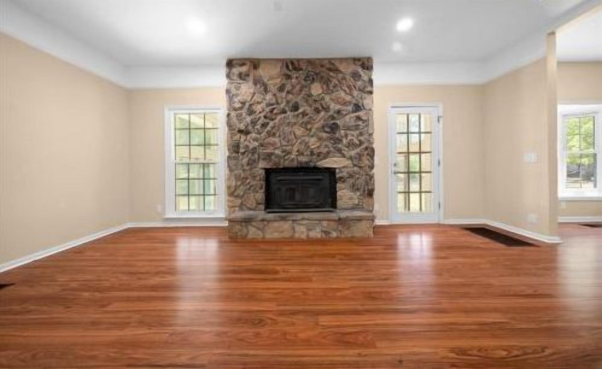 Spacious living room with hardwood floors and a stunning stone fireplace