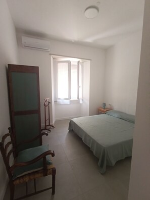 A bedroom with a bed, a chair, a window, and a nightstand. - Apartment 2 minutes from the ocean, public beach, and home amenities (Terracina)