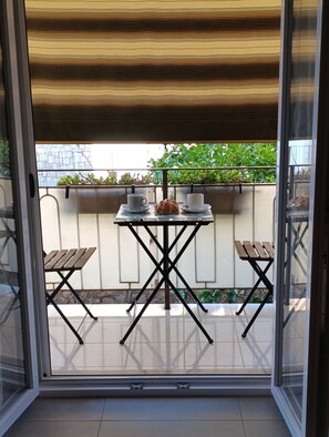 A balcony with a table and chairs, a potted plant, and a view of greenery. - Apartment 2 minutes from the ocean, public beach, and home amenities (Terracina)