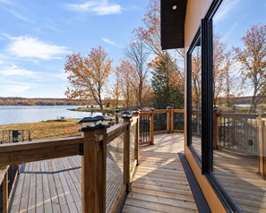 A wooden deck with a view of a lake and autumn trees.