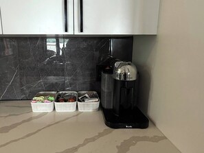 Eine Küche mit Kaffeemaschine, Küchenutensilien in Körben und einer Marmor-Spritzschutzwand.