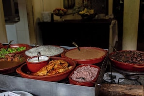 Een buffet met diverse gerechten, waaronder rijst, bonen en vlees.