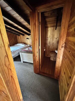 Een houten interieur met een slaapkamer en een badkamer.