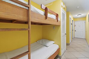A bunk bed room with a wooden frame, white bedding, and a yellow wall. - Summer Breeze 103 (Miramar Beach)