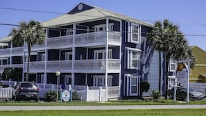 A multi-story building with balconies, a sign for 'Summer Breeze,' and a white picket fence. - Summer Breeze 103 (Miramar Beach)