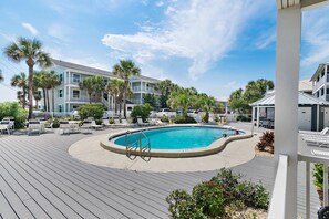 A pool area with lounge chairs and a building with balconies. - Summer Breeze 103 (Miramar Beach)