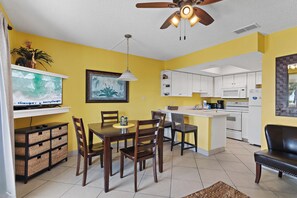 A compact living space with a dining area, kitchen, and a ceiling fan. - Summer Breeze 103 (Miramar Beach)