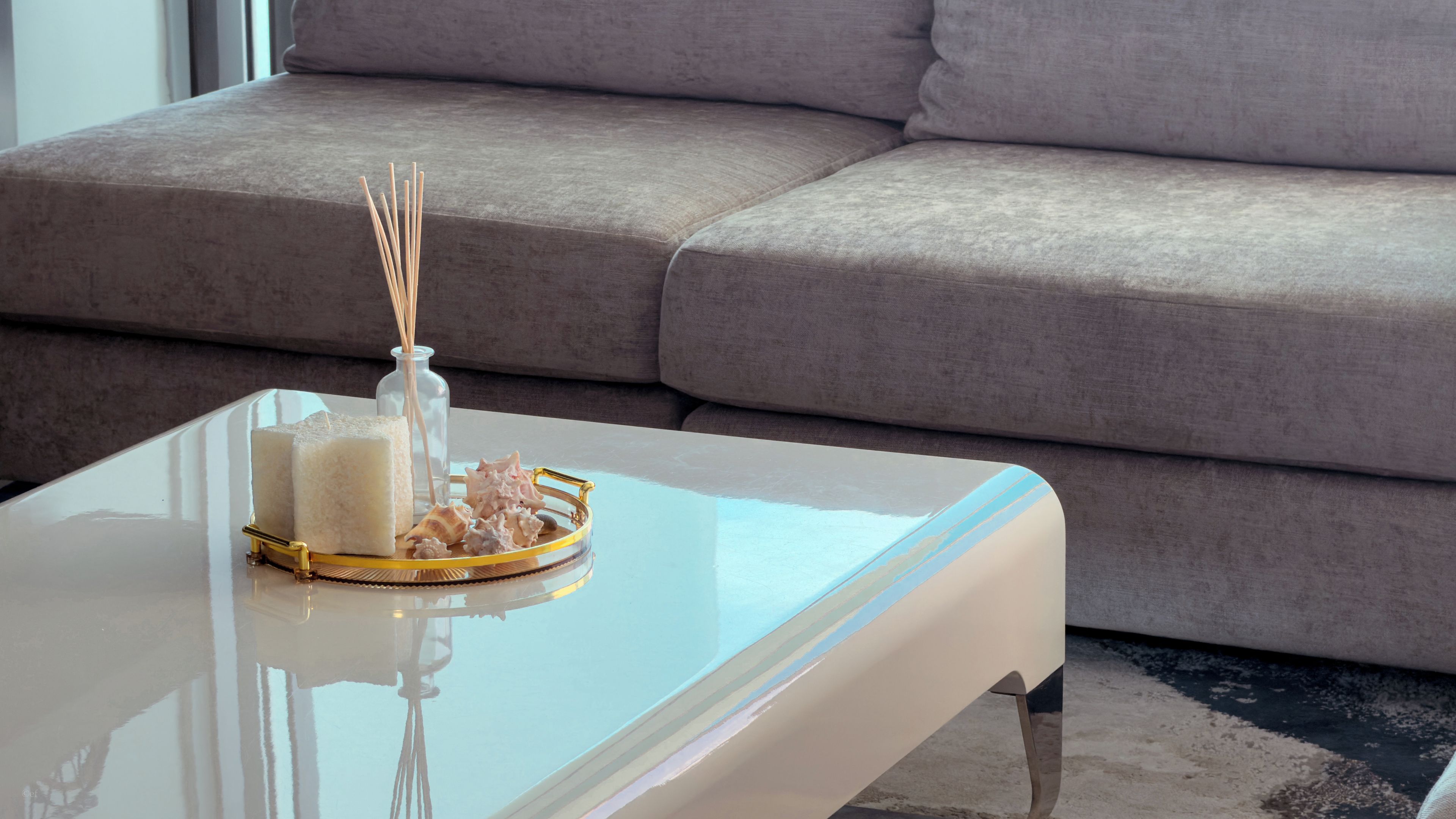 Un salon moderne avec une table basse blanche, un vase en verre et des objets décoratifs.
