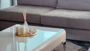 Una sala moderna con una mesa de centro blanca, un florero de vidrio y objetos decorativos.