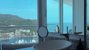 A bathroom with a large window, a round mirror, and a modern sink.