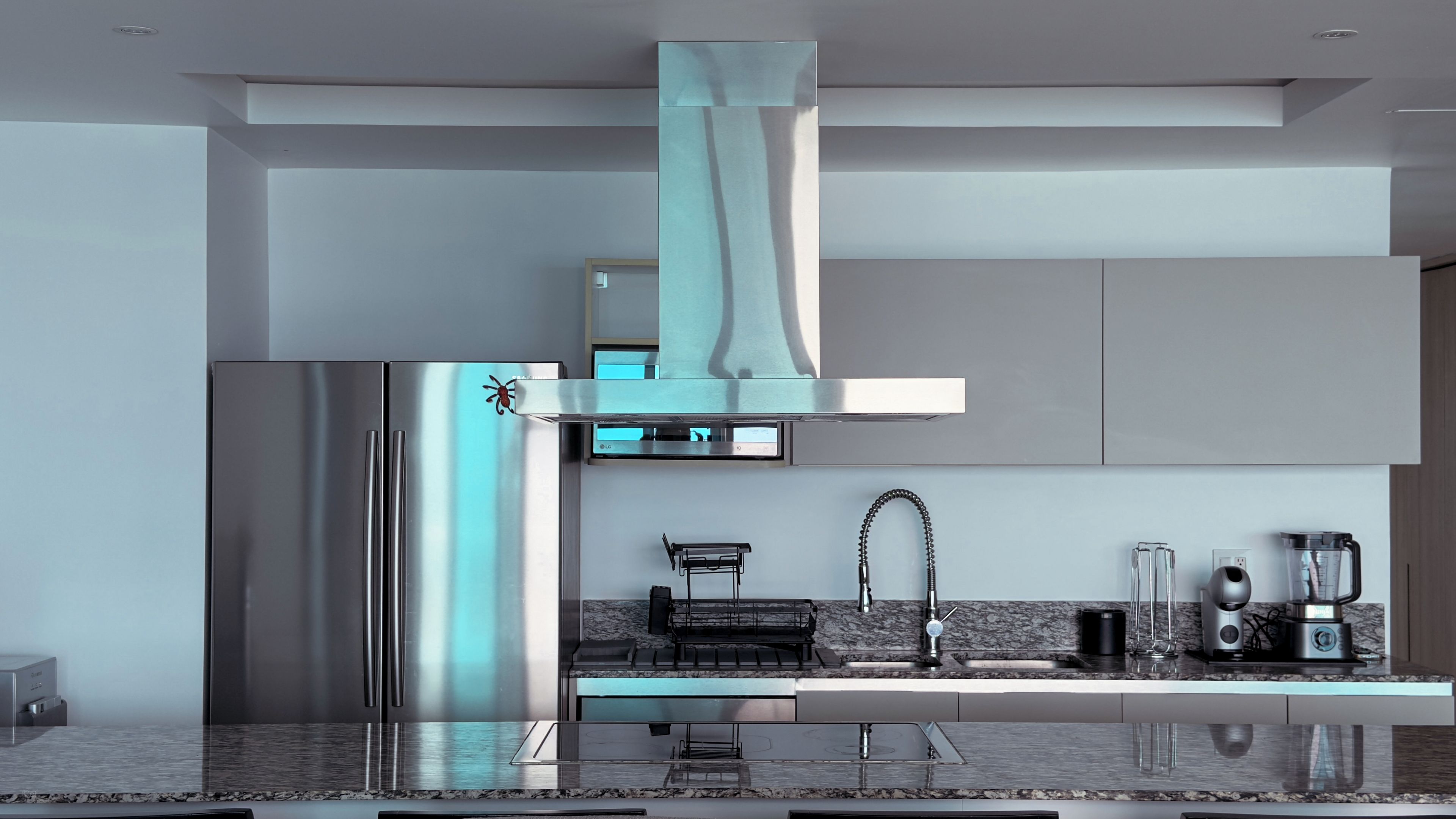 A modern kitchen with stainless steel appliances, a marble countertop, and a built-in oven.