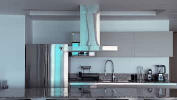 A modern kitchen with stainless steel appliances, a marble countertop, and a built-in oven.