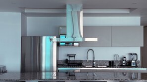 Una cocina moderna con electrodomésticos de acero inoxidable, encimera de mármol y horno empotrado.