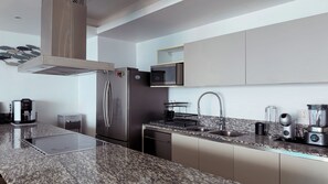 A modern kitchen with a stainless steel refrigerator, a built-in microwave, and a granite countertop.