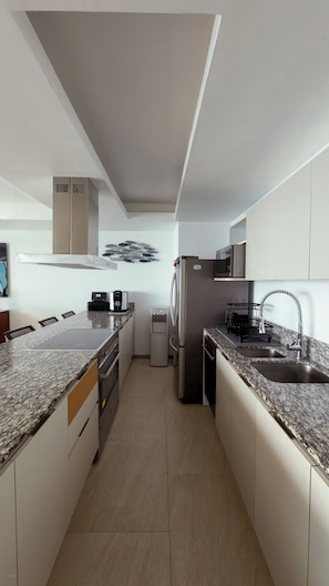 Una cocina moderna con una isla central, electrodomésticos de acero inoxidable y un microondas integrado.