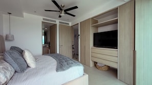 A bedroom with a bed, a ceiling fan, a TV, and built-in wardrobes.