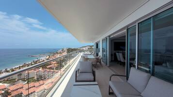 Un balcón con vista al mar y edificios, amueblado con una mesa y sillas.