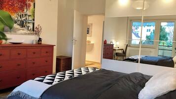 A bedroom with a bed, a dresser, a mirror, and a painting on the wall.