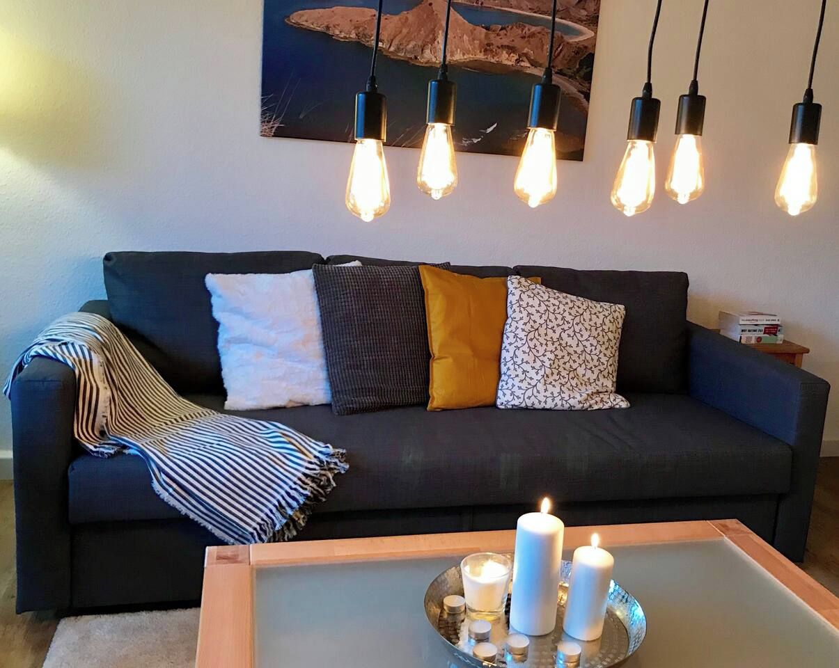 Ein dunkelgraues Sofa mit vielen Kissen und einer gestreiften Decke.