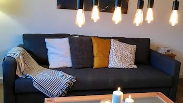 Ein dunkelgraues Sofa mit vielen Kissen und einer gestreiften Decke.