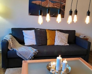 Ein dunkelgraues Sofa mit vielen Kissen und einer gestreiften Decke.