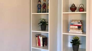 Ein Zimmer mit zwei weißen Bücherregalen, eines mit Figuren, das andere mit Büchern und einer roten Teekanne.