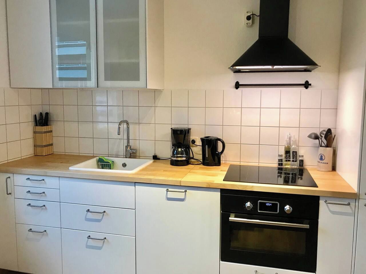 Eine Küche mit weißen Schränken, einem schwarzen Herd und einer Kaffeemaschine.