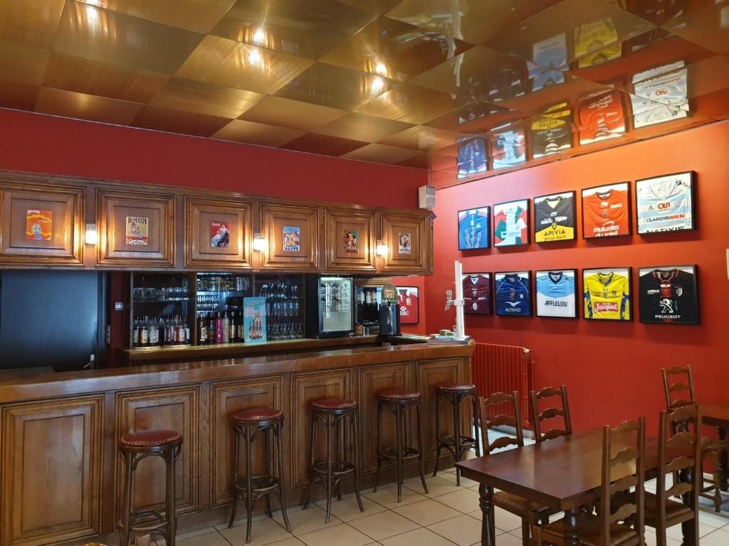 Un coin bar avec des tabourets en bois et un comptoir, une table à manger avec des chaises, et des tableaux encadrés accrochés au mur.