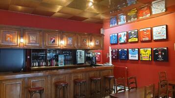 Una zona de bar con taburetes de madera y una barra, una mesa de comedor con sillas y cuadros en la pared.