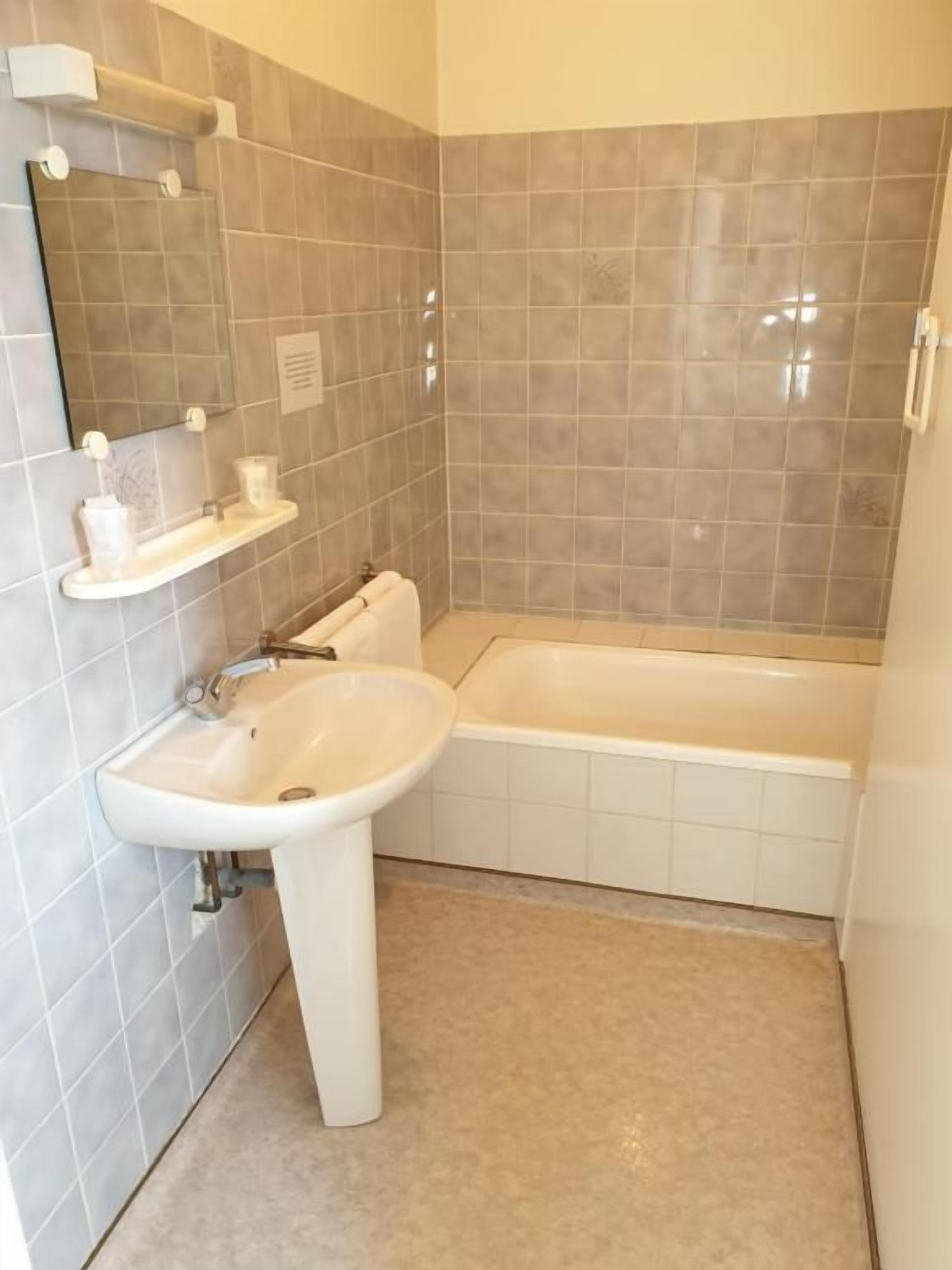Une salle de bain avec un lavabo, un miroir et une baignoire.