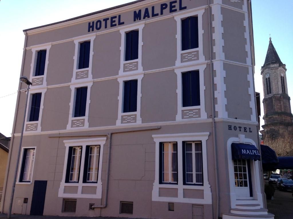 Un edificio con il cartello 'HOTEL MALPEL' e una torre sullo sfondo.