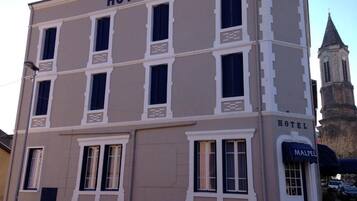 Un edificio con il cartello 'HOTEL MALPEL' e una torre sullo sfondo.