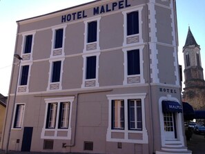 A building with the sign 'HOTEL MALPEL' and a tower in the background.