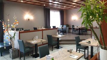 Un restaurante con cabinas y mesas, techo de madera y plantas en macetas.