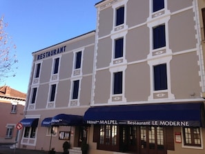 Un immeuble avec un restaurant au rez-de-chaussée et un hôtel doté d’une marquise bleue.