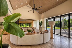 A spacious living room with a large window, a ceiling fan, and a view of a swimming pool. - Villa Flamboyan- Wonderful house in enchanting Casa de Campo (Casa de Campo)