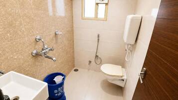 A small bathroom with a toilet, a sink, a shower, and a window.