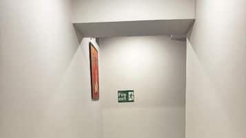 Un pasillo estrecho con un letrero de salida de incendios y una puerta al final.