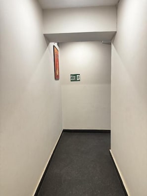 Passadís estret amb senyal de sortida d'incendis i una porta al final.