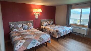 Une chambre avec deux lits, un mur rouge, une fenêtre donnant sur un paysage agréable et un luminaire au plafond.