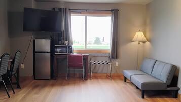 Un espacio habitable compacto con kitchenette, televisor de pantalla plana, sofá y comedor con sillas.