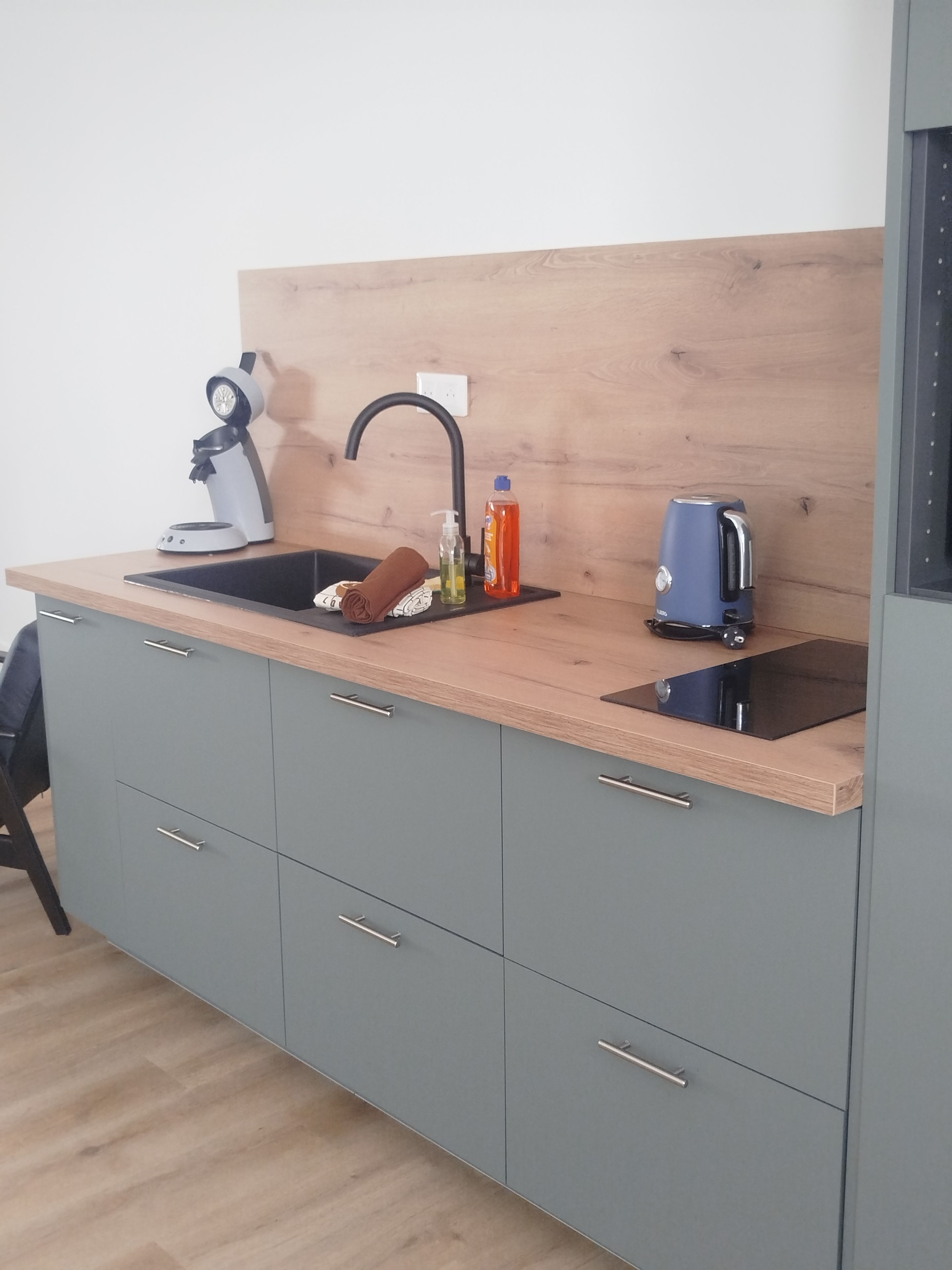 A modern kitchen with a sink, a kettle, and a bottle of dish soap.
