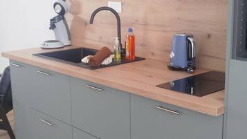 A modern kitchen with a sink, a kettle, and a bottle of dish soap.