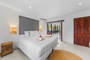 Ein modernes Schlafzimmer mit einem großen Bett, Nachttischlampen und Blick ins Freie.