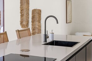 Eine moderne Küche mit einem eleganten schwarzen Spülbecken, einem Edelstahlarmaturen und einer weißen Arbeitsplatte.
