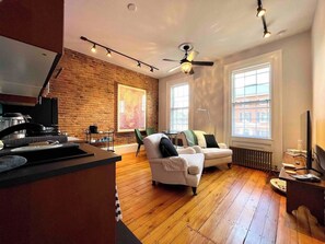 Ein modernes Wohnzimmer mit Backsteinwand, Deckenventilator, Sofa, Couchtisch und Fernseher.