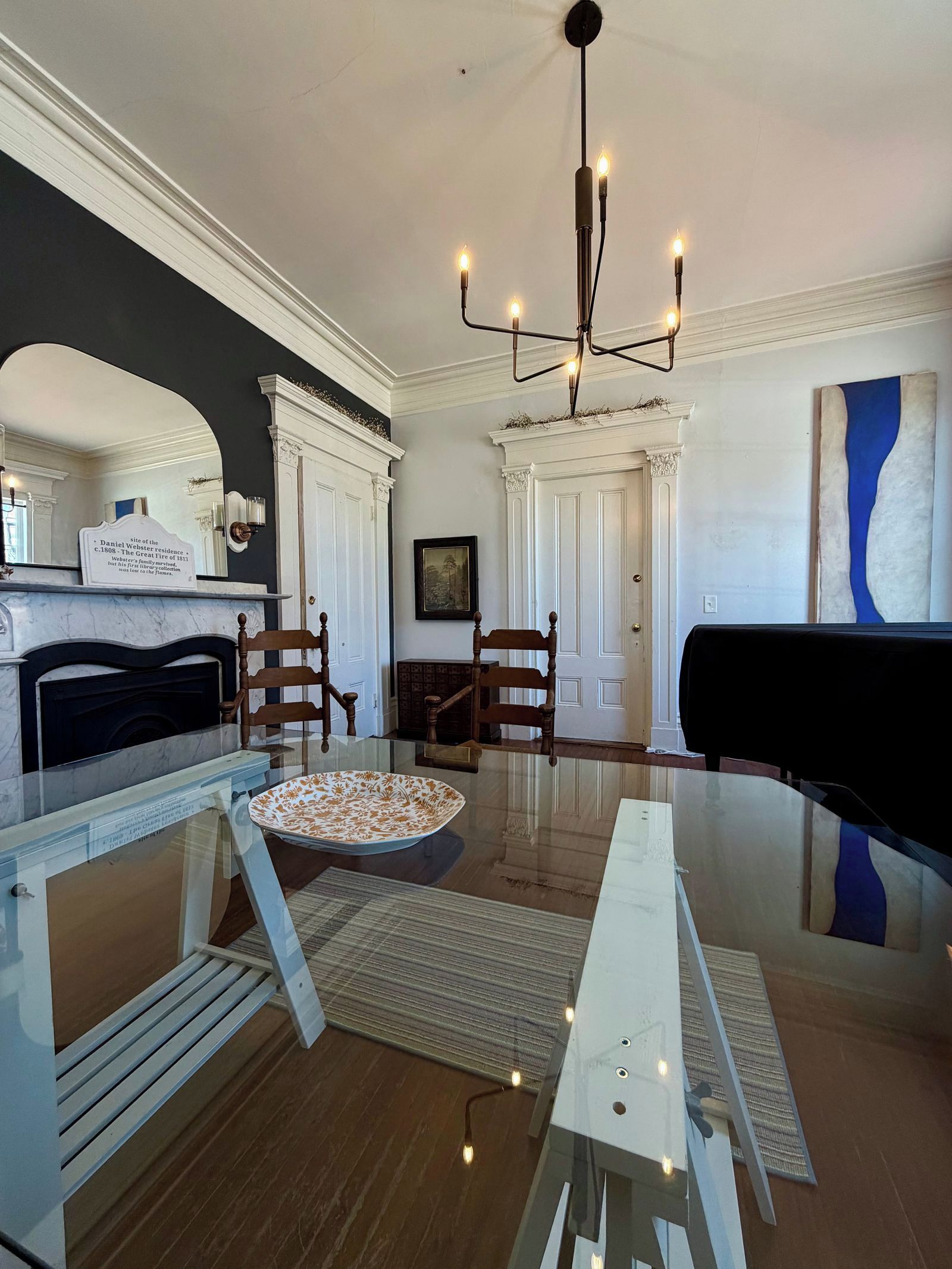 Un salon avec une cheminée, un piano et une table à manger.