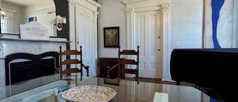 Un salon avec une cheminée, un piano et une table à manger.