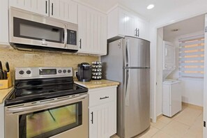 A kitchen with white cabinets, a stainless steel refrigerator, a microwave, an oven, and a coffee maker. - Cozy Ground Level Condo w/ Pool | Princesa E-103 (Puerto Peñasco)
